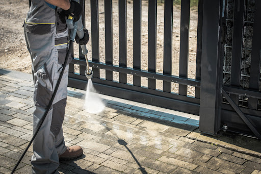 A close-up of a professional pressure washing a brick floor.